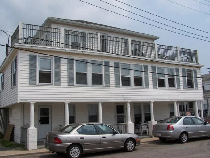 two cars parked in front of a two story house.