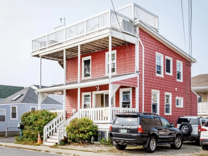 two cars parked in front of a red house.