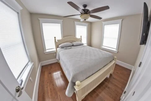 a bed room with a neatly made bed and a ceiling fan.