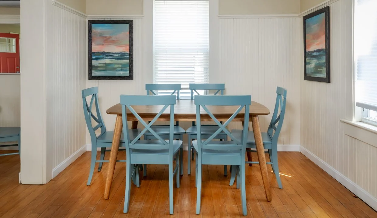 a dining room table with blue chairs and a picture on the wall.