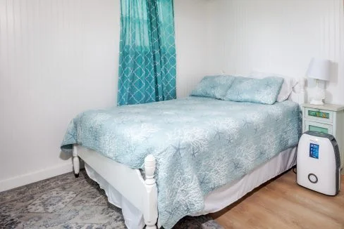 a bed with a blue comforter and a white night stand.
