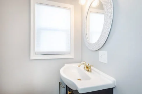 A bathroom with a sink, mirror, and window.