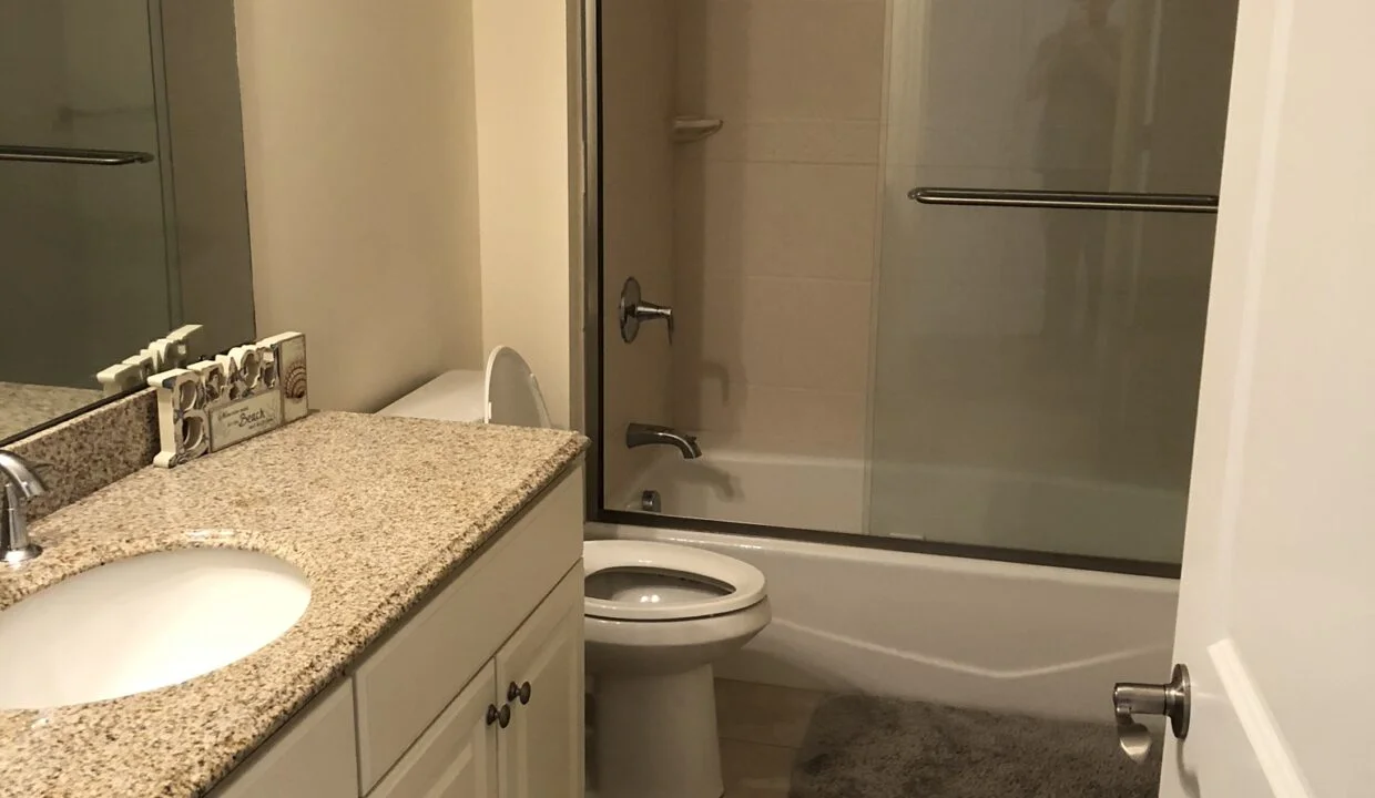 a bathroom with a toilet, sink, and shower.