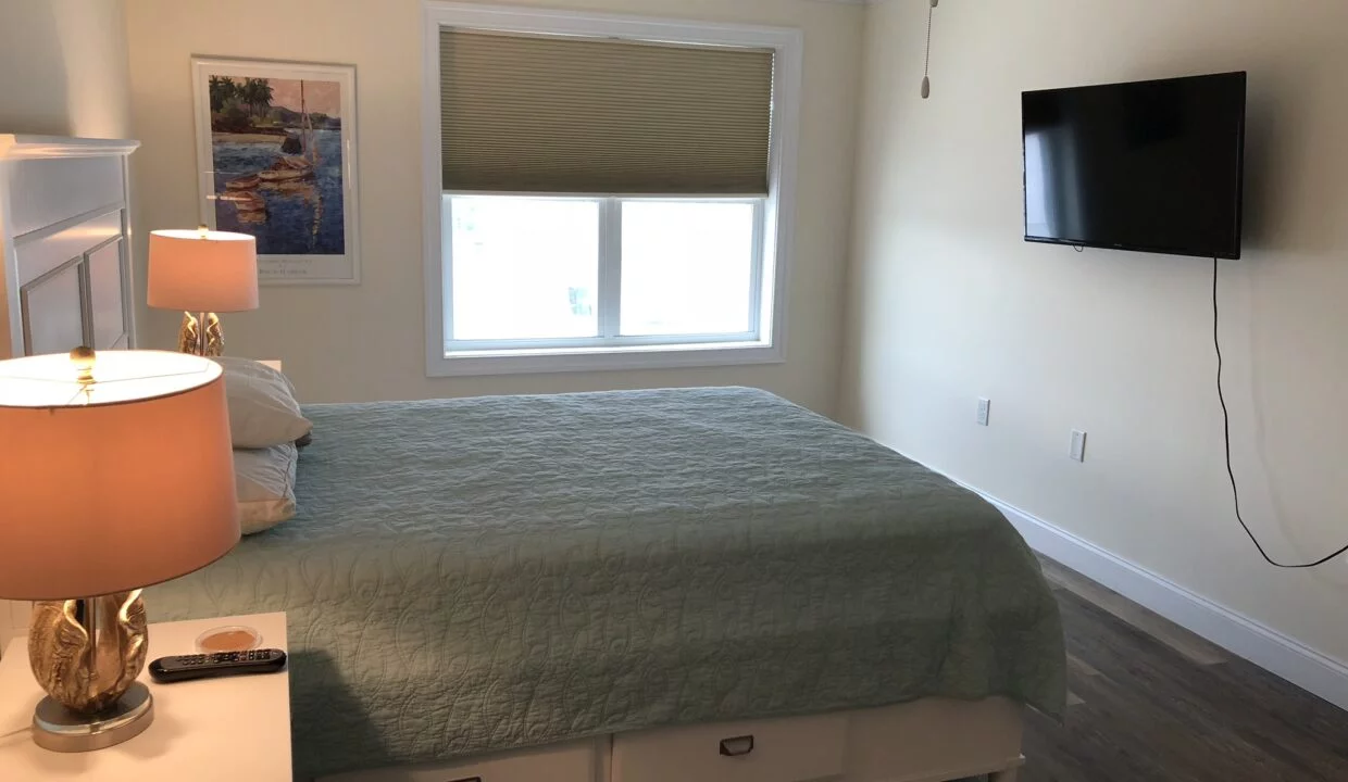 a bed room with a neatly made bed and a flat screen tv.