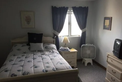 a bed room with a neatly made bed and a flat screen tv.