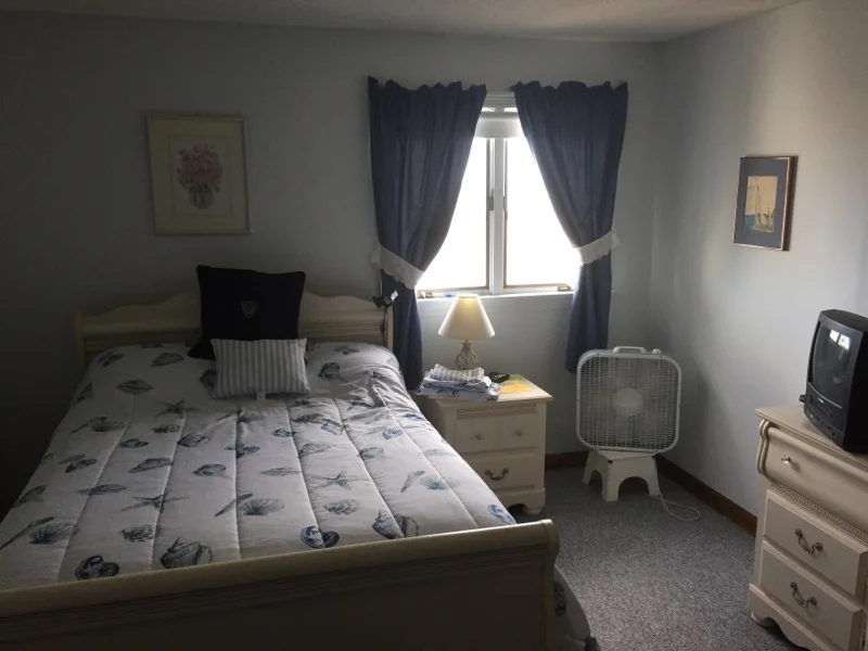 a bed room with a neatly made bed and a flat screen tv.