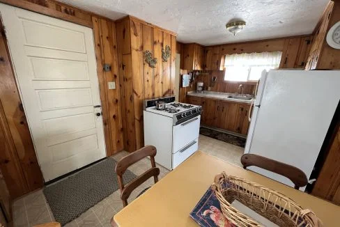 a kitchen with a table, stove, and refrigerator.