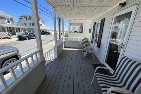 a couple of chairs sitting on top of a wooden porch.