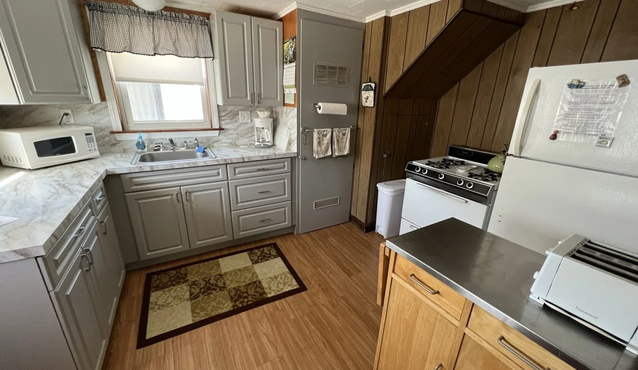 a kitchen with a stove, refrigerator, microwave, and sink.