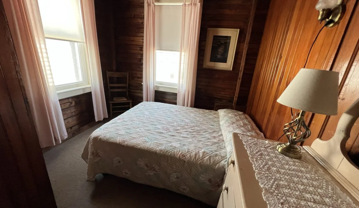 a bedroom with wood paneling and a white bed.