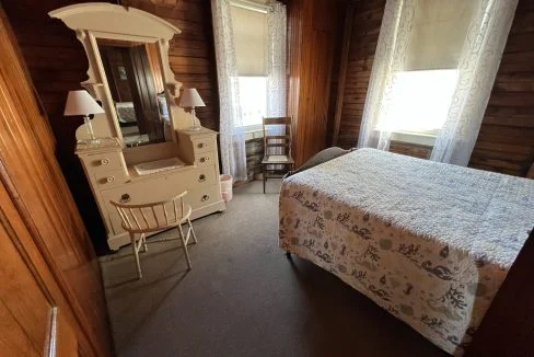 a bedroom with a bed, dresser and mirror.