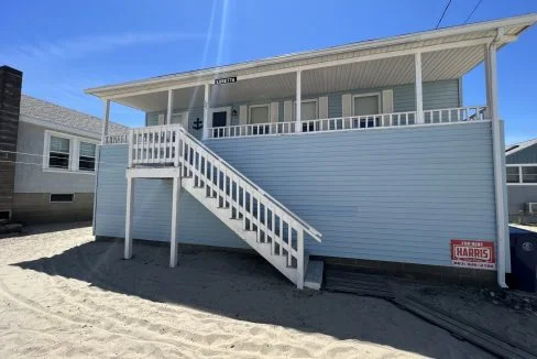 a beach house with a white staircase leading up to it.