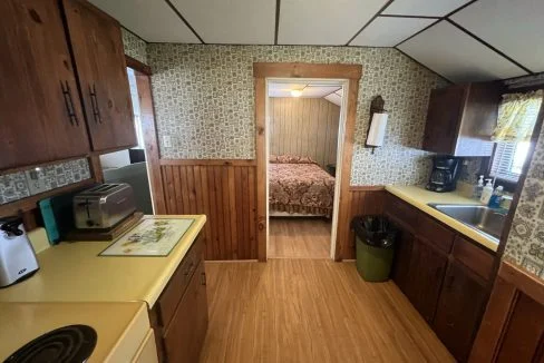 a kitchen with a sink, stove, microwave and a bed.
