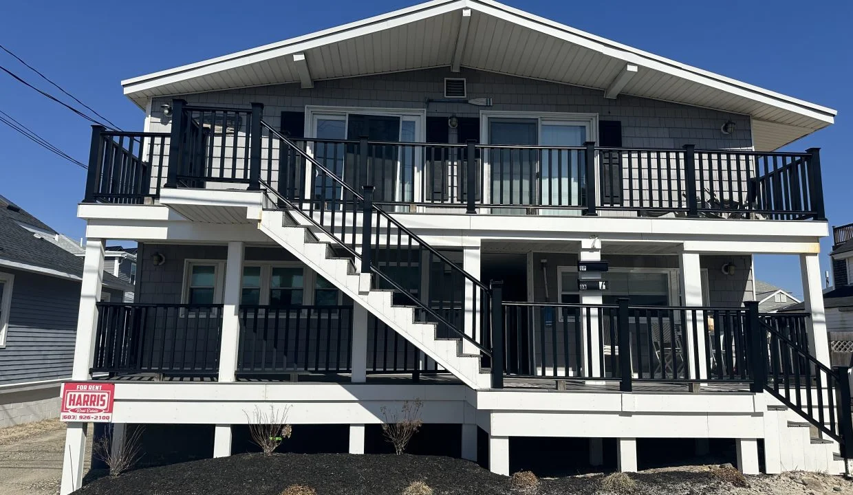 Two-story house with a black balcony railing and an external staircase leading to the upper floor.