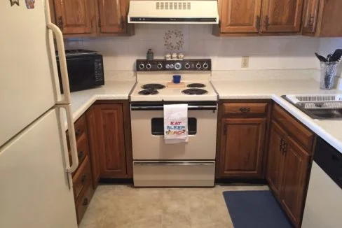 a kitchen with a stove, refrigerator, and microwave.