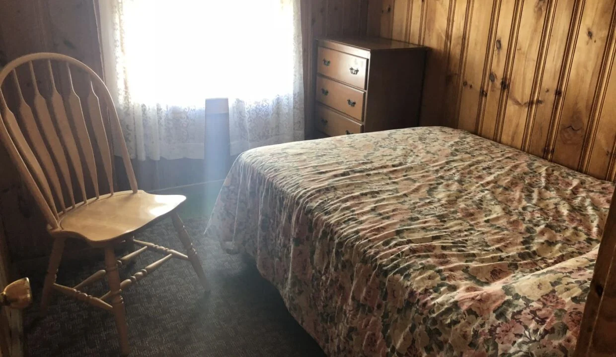 a bedroom with a bed, dresser and chair.