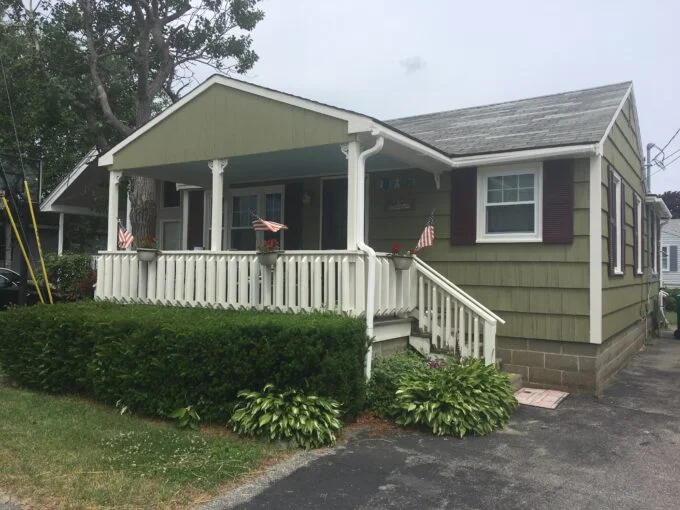 a house with a white porch and red shutters.