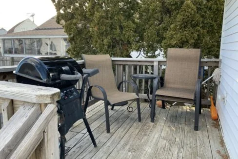 a deck with chairs and a grill on it.