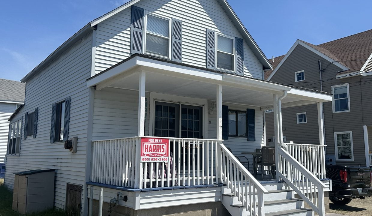 A white two-story house with a large front porch featuring a 