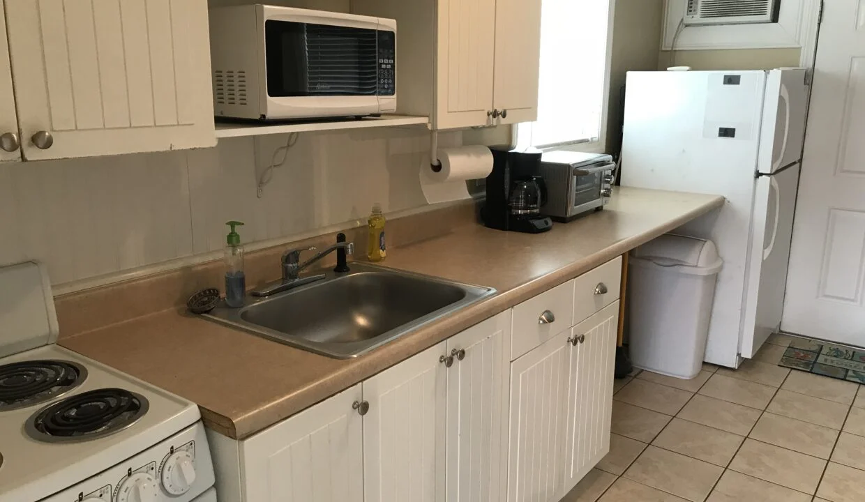 a kitchen with a sink, stove, microwave and refrigerator.