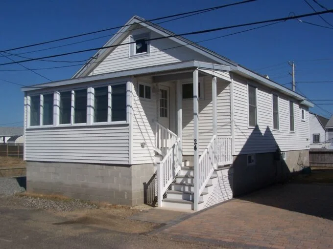 a small white house with a porch and stairs.