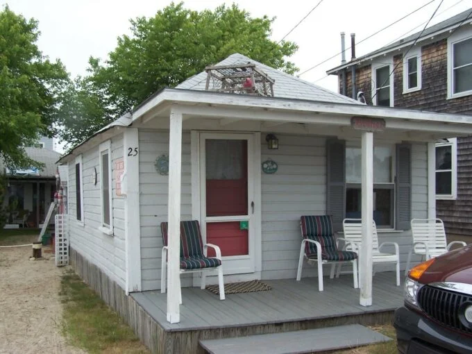 a small house with two chairs on the porch.