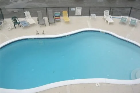 an empty swimming pool with chairs around it.