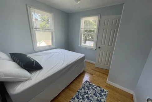 a bed sitting in a bedroom next to two windows.