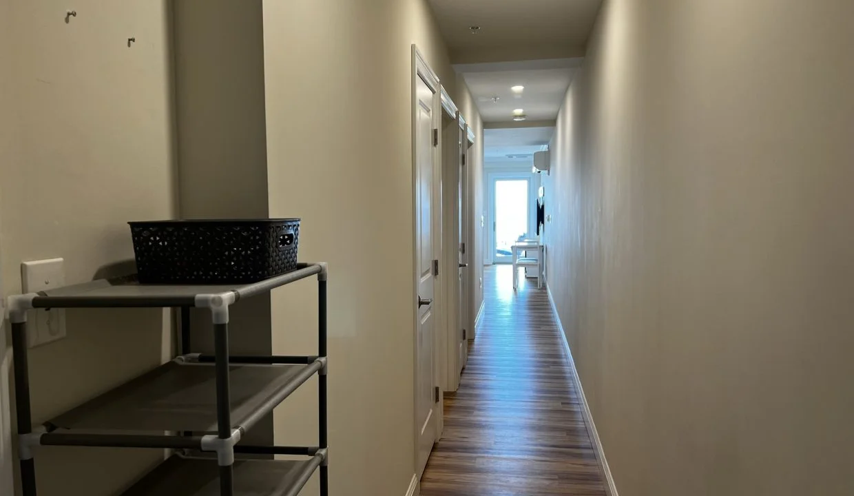 a long hallway with a shelf and a basket.