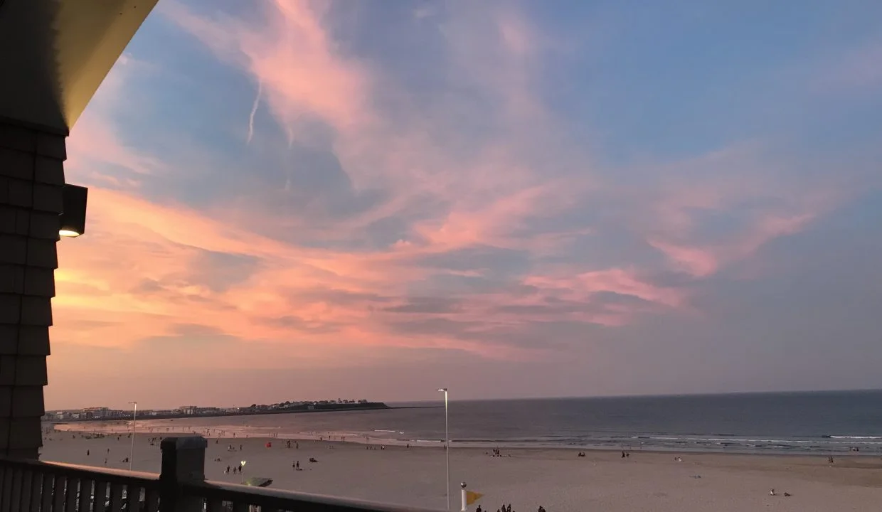 A balcony overlooking the beach at sunset.