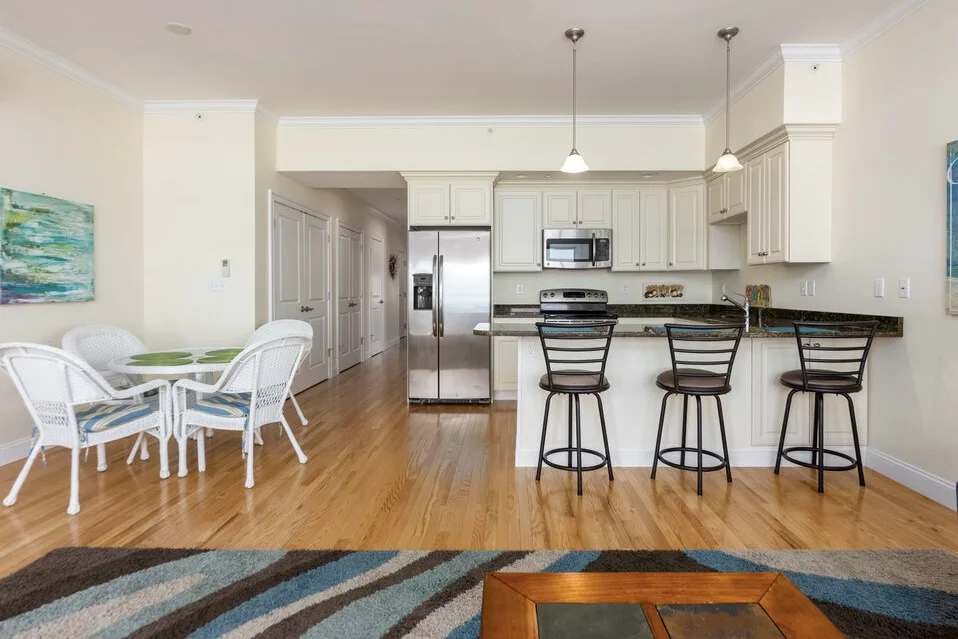 A kitchen and dining area with a bar stools.