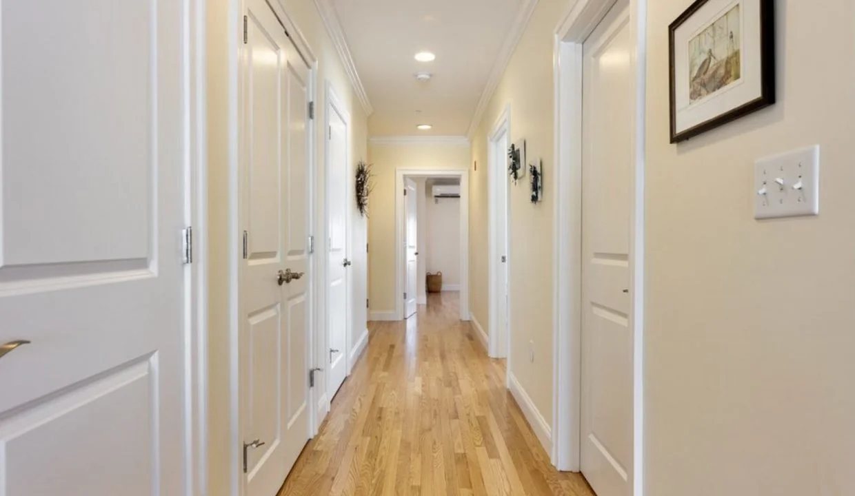 A hallway with white doors and hardwood floors.