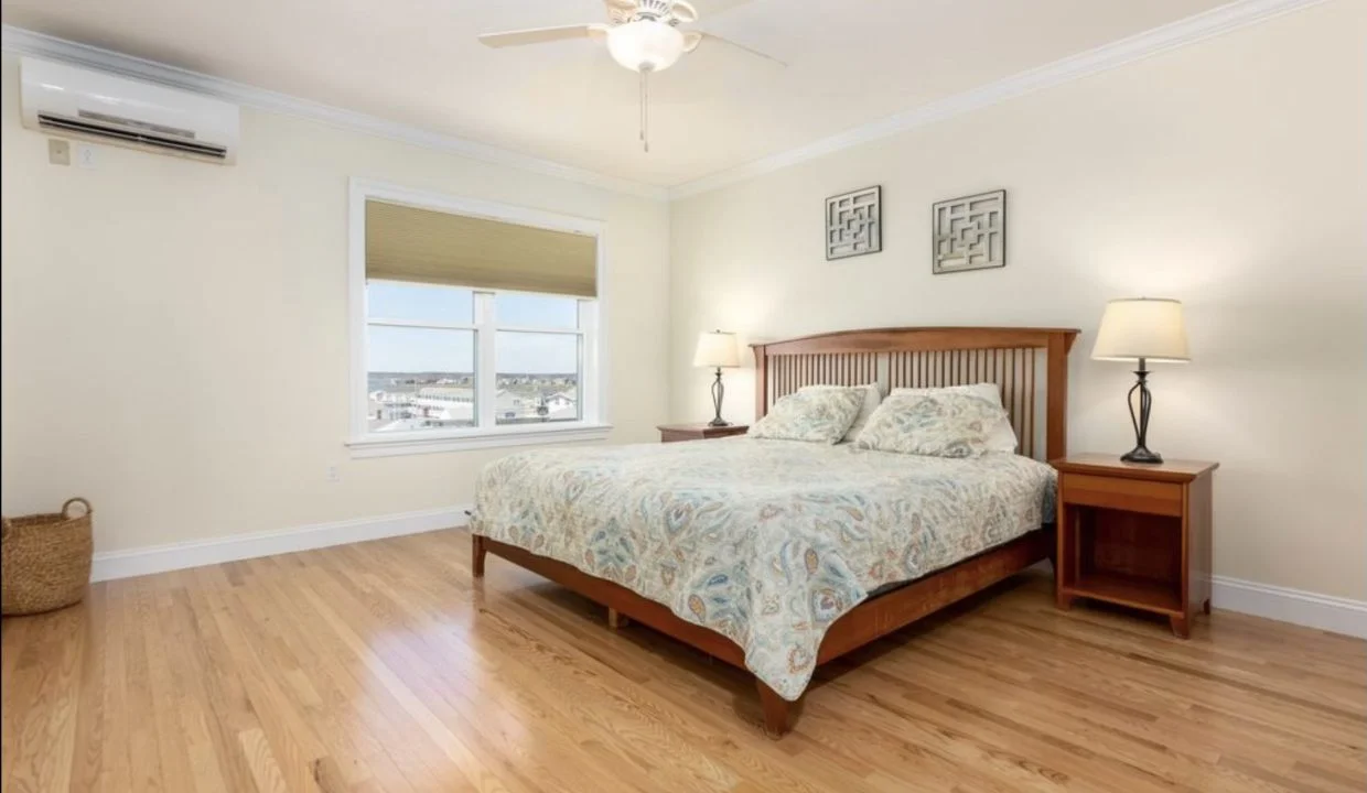 A bedroom with hardwood floors and a ceiling fan.