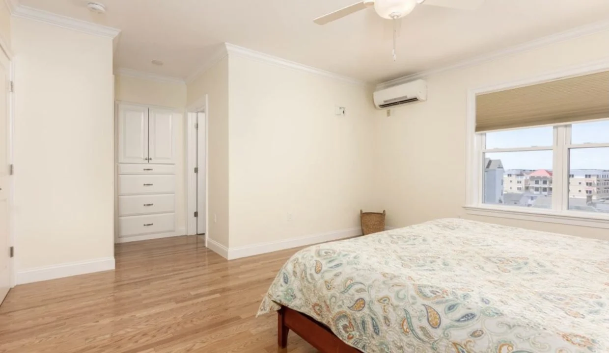 A bedroom with hardwood floors and a ceiling fan.