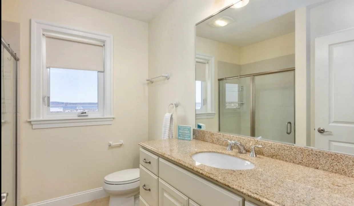 A bathroom with granite counter tops and a window.