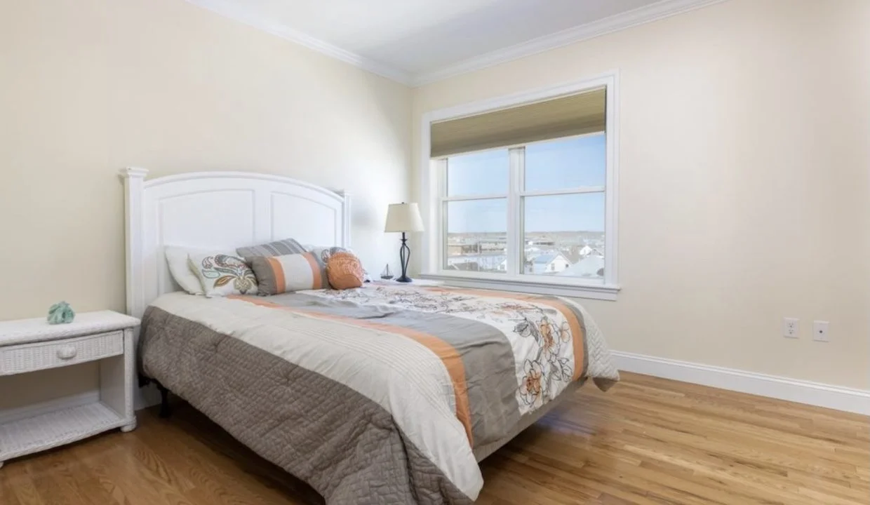 A bedroom with hardwood floors and a window.