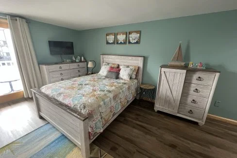 a bed room with a neatly made bed and a dresser.