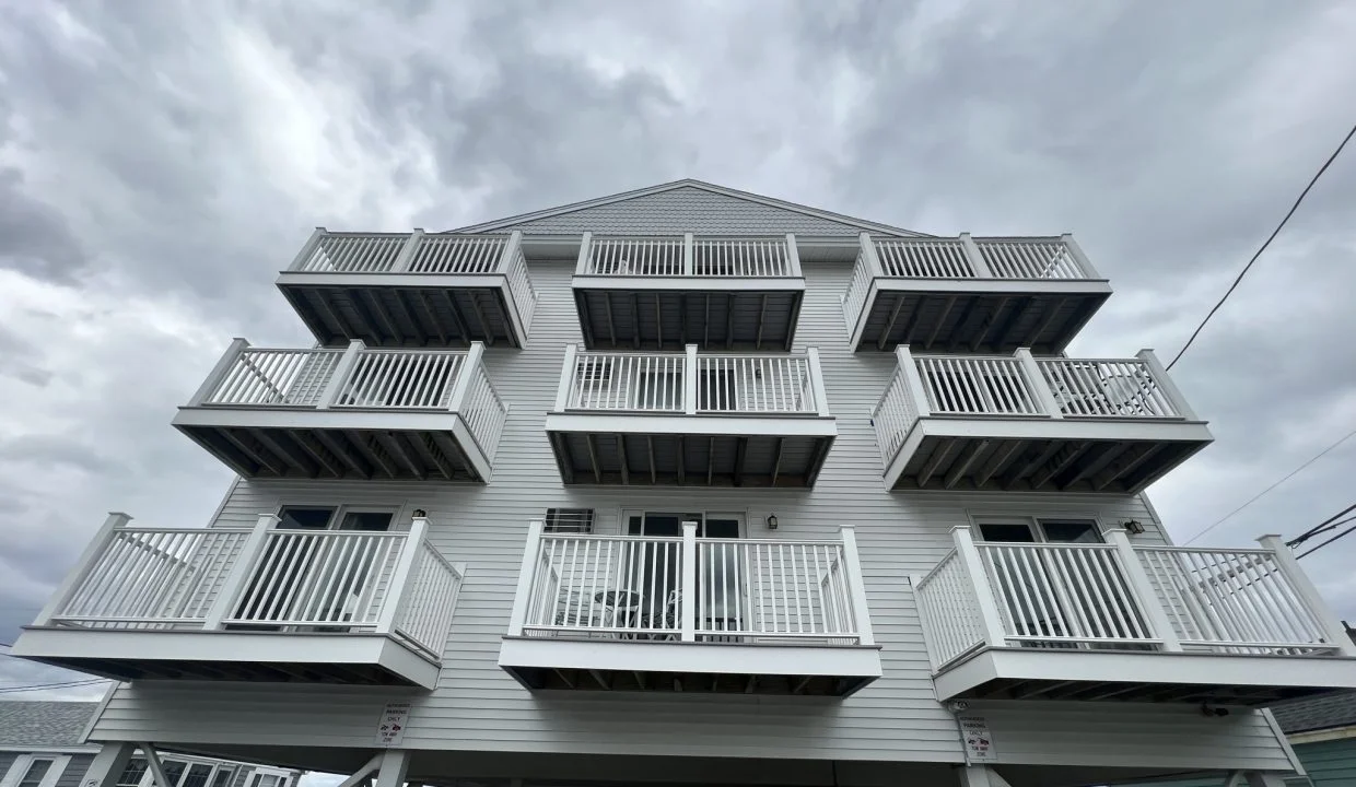 a tall white building with balconies on top of it.