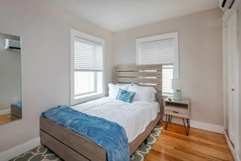 a bed sitting in a bedroom next to two windows.