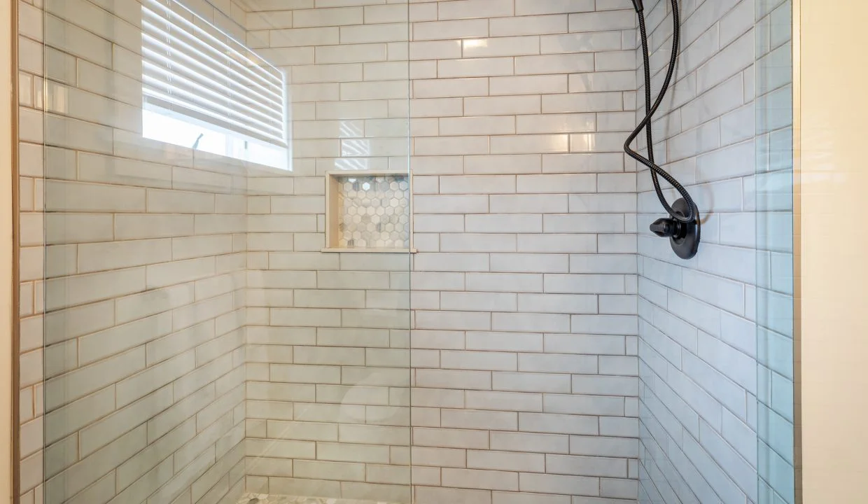 a white tiled shower with a glass door.