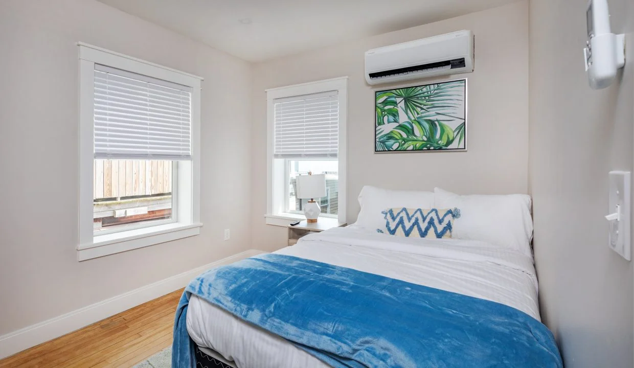 a bedroom with a bed, window, and air conditioner.