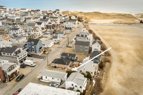 Aerial view of a coastal neighborhood with tightly packed houses adjacent to a sandy beach.