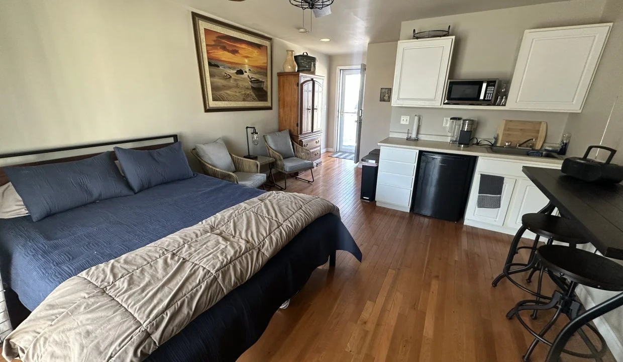 a bed sitting in a bedroom next to a kitchen.