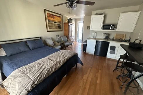 a bed sitting in a bedroom next to a kitchen.