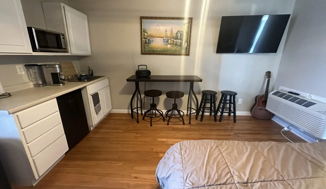 a bed sitting in a bedroom next to a kitchen.