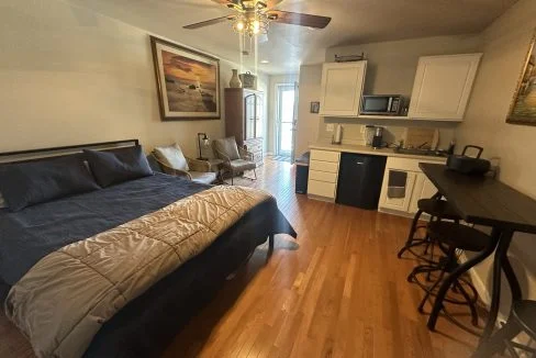 a bed sitting in a bedroom next to a kitchen.