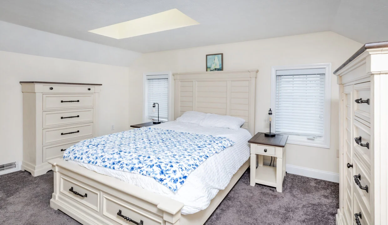 a bedroom with a bed, dressers and a window.