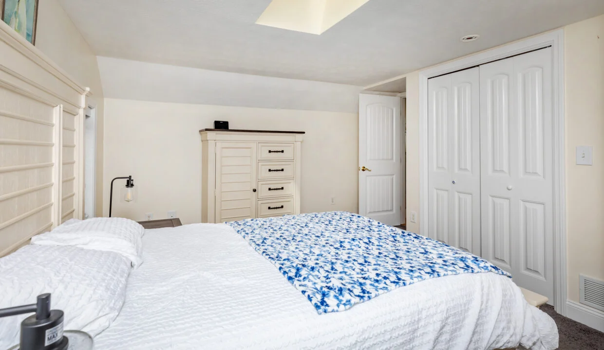 a bedroom with a bed, dresser, and closet.