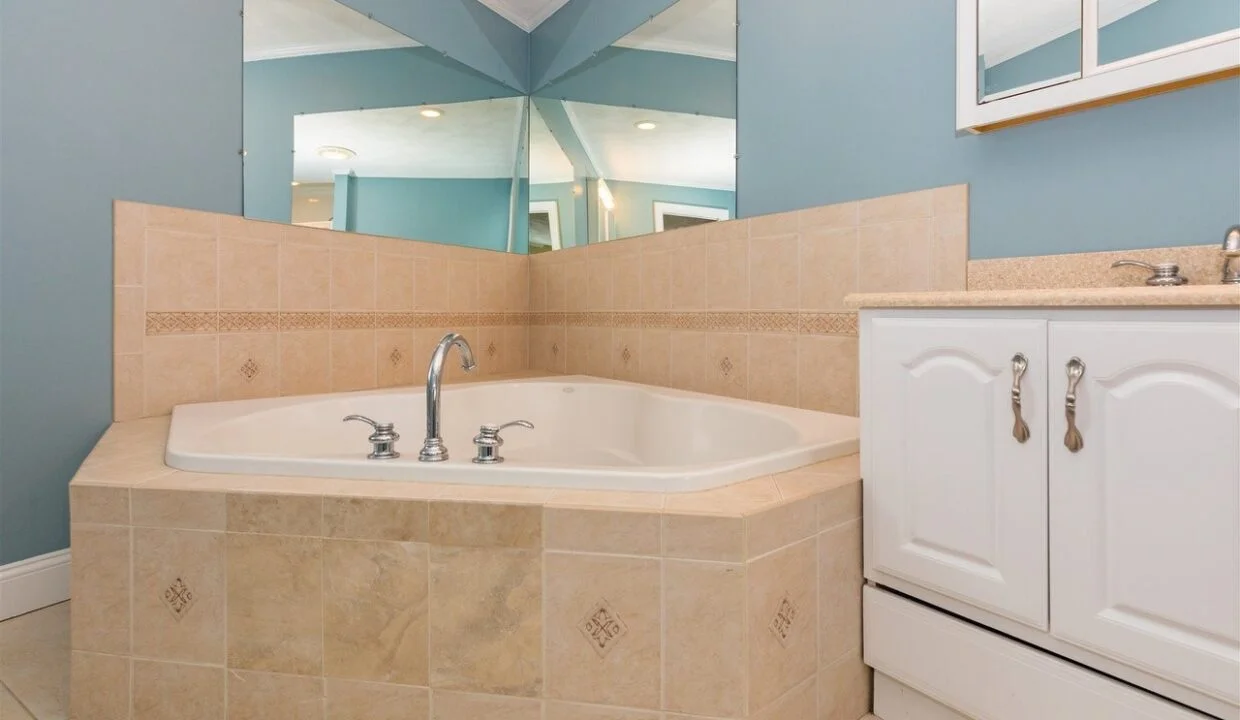 a bathroom with a bathtub, sink and mirror.