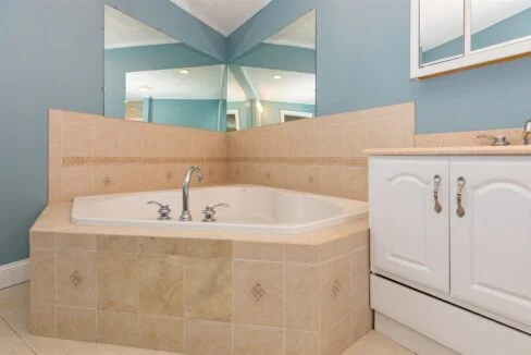 a bathroom with a bathtub, sink and mirror.